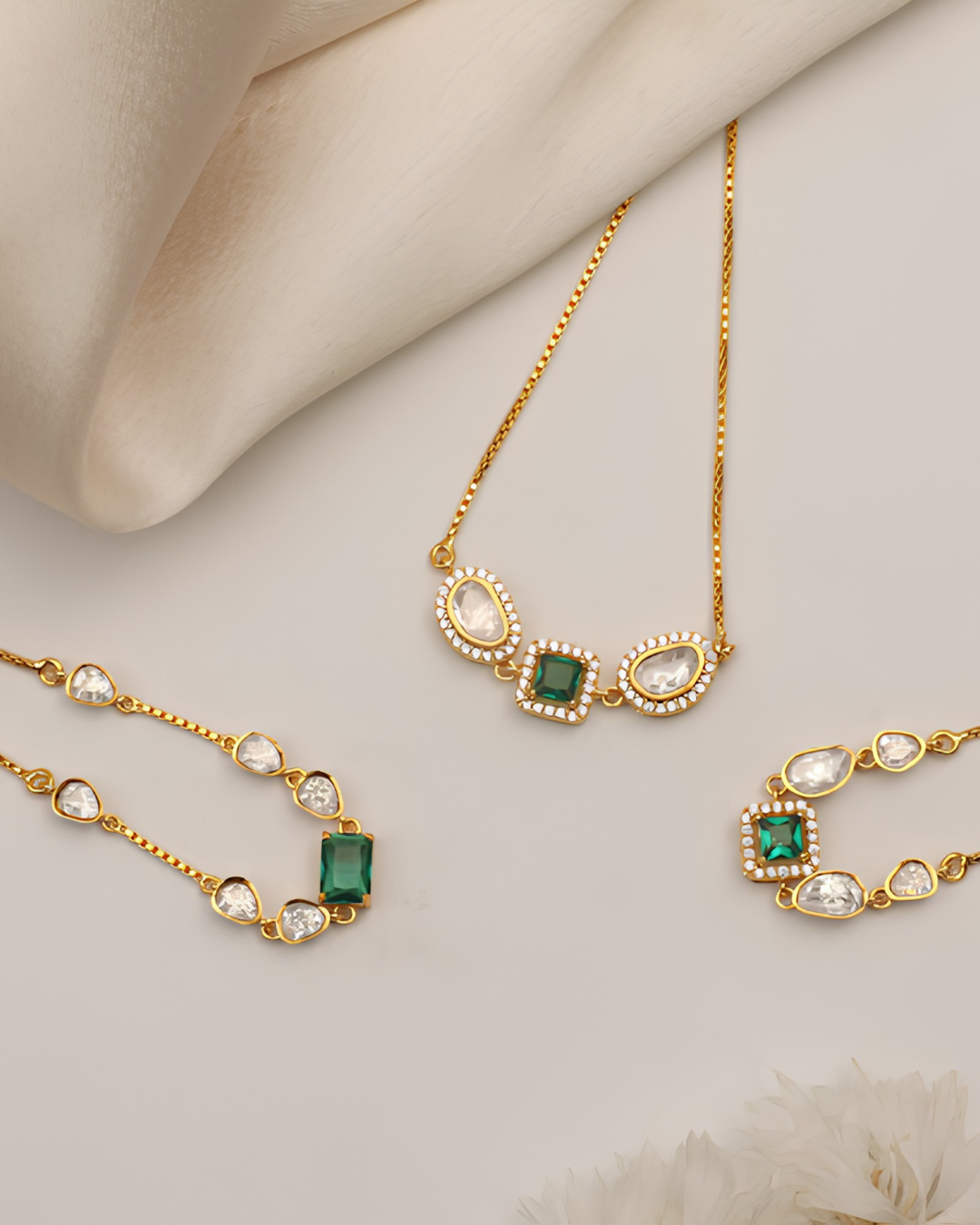Stylish jewelry set combining radiant pearls, green gemstones, and intricate gold craftsmanship.
