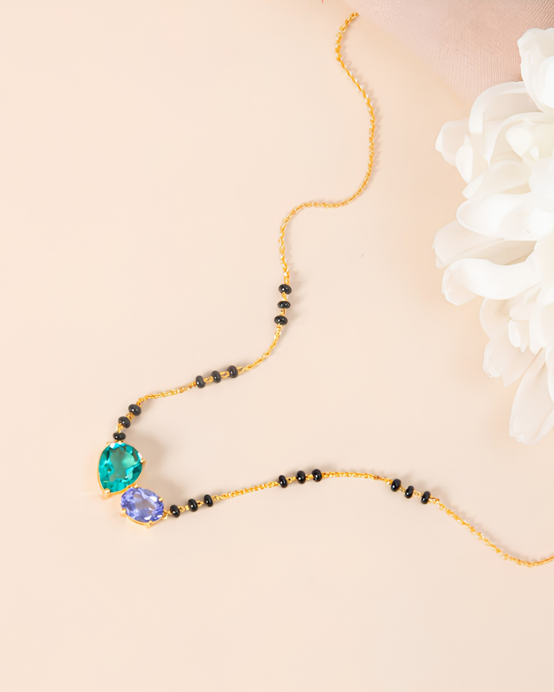 Black bead necklace with green and purple gemstones.