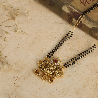 Black beaded mangalsutra with an intricate gold-toned floral pendant.