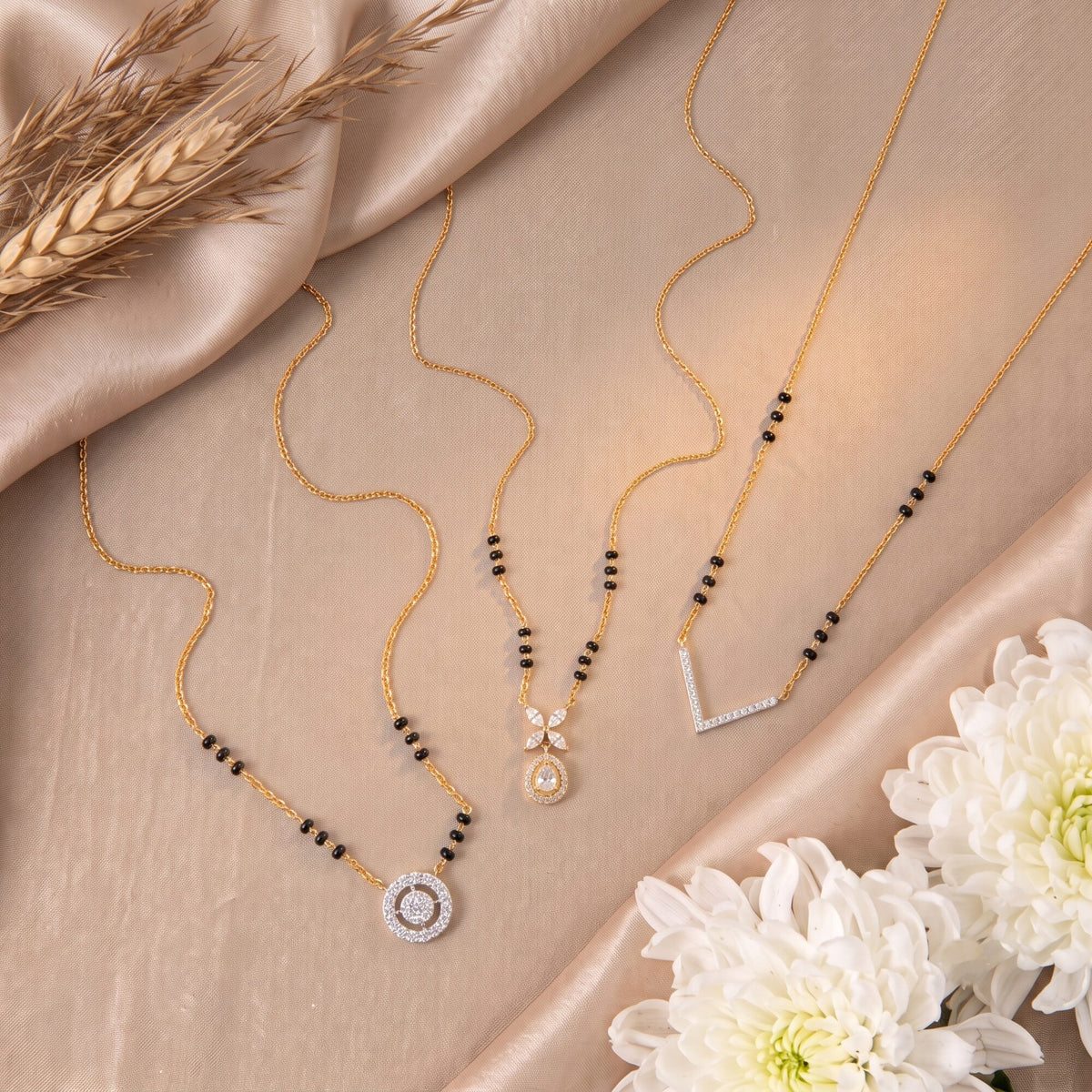 Three gold-plated silver mangalsutras on silk
