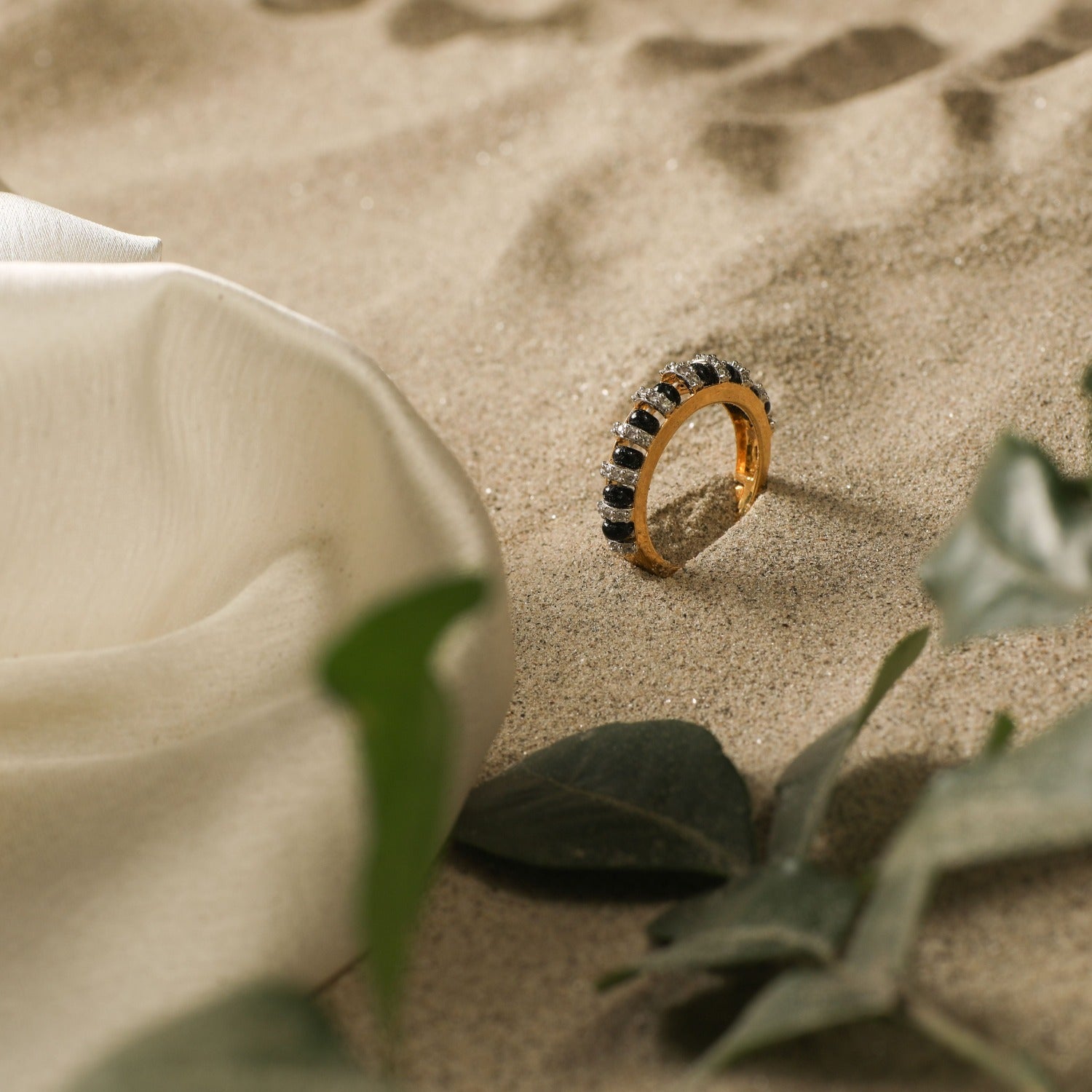 A picture of a silver finger band with black beads and Cubic Zirconia on a white background.