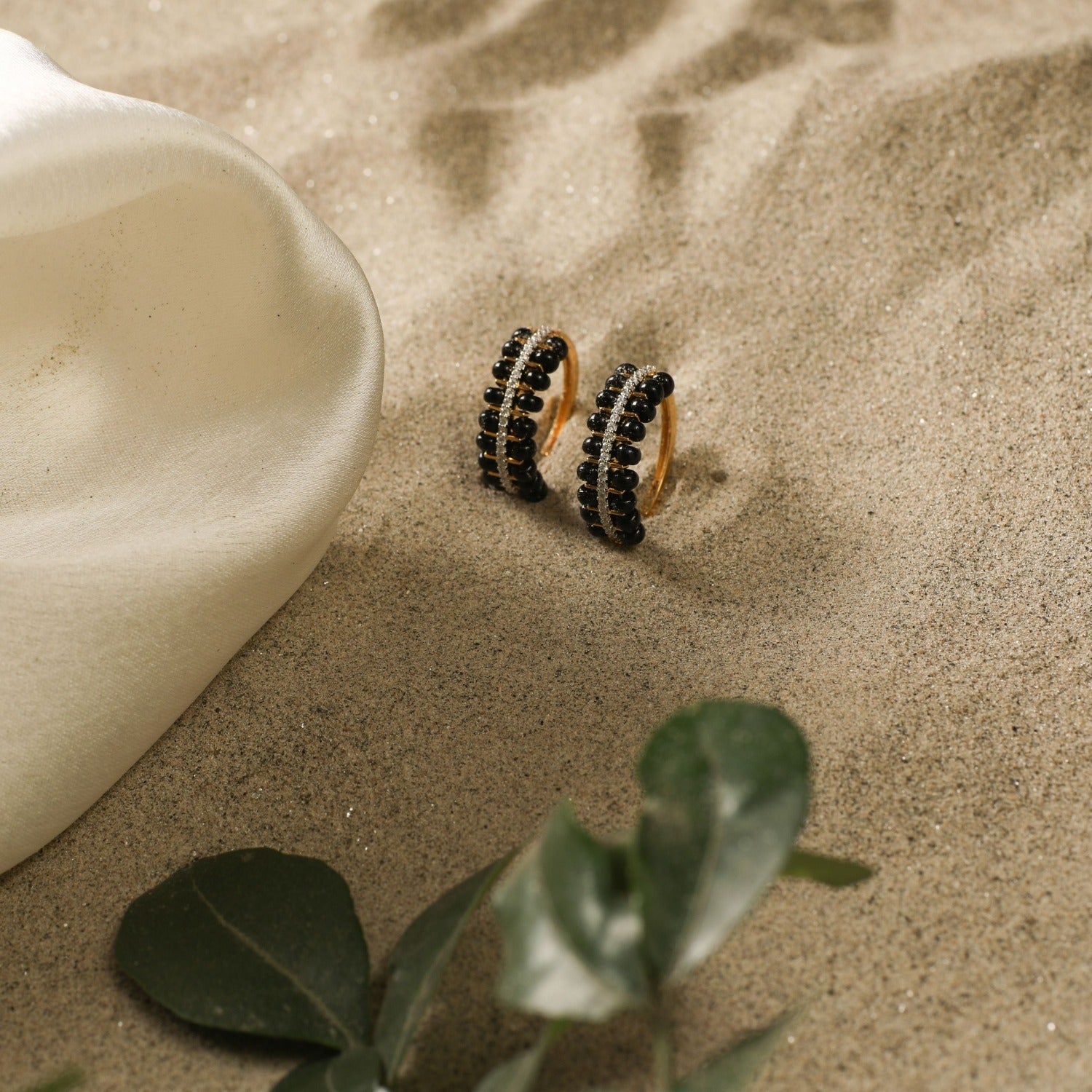 A picture of a silver hoop earrings with black beads and Cubic Zirconia on a white background.