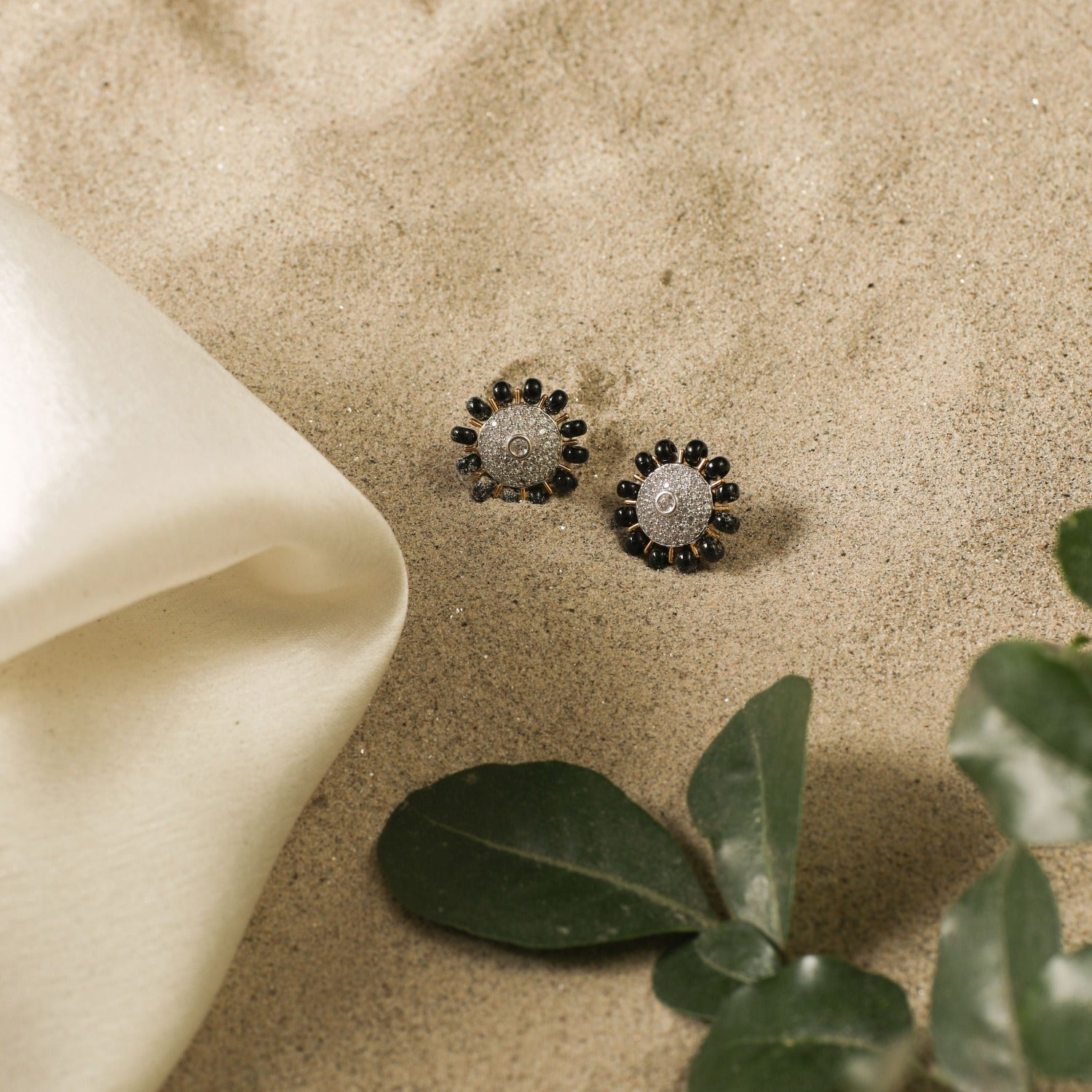 A picture of silver earrings with black beads and Cubic Zirconia in a floral design on a white background.