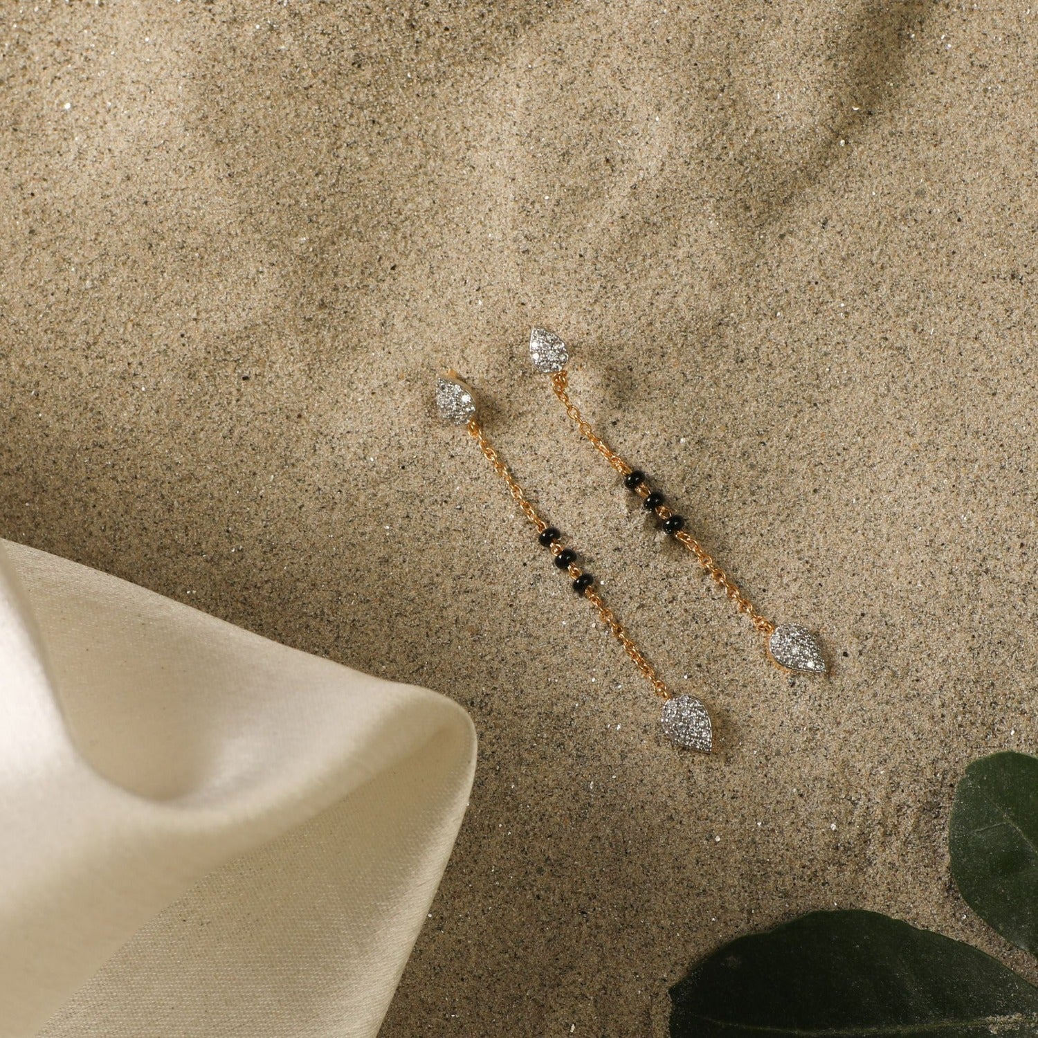 A picture of gold plated silver earrings with black beads and Cubic Zirconia on a white background.
