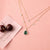 A picture of a double layered silver necklace with a teardrop-shaped pendant featuring green gemstone and Cubic Zirconia on a white background.